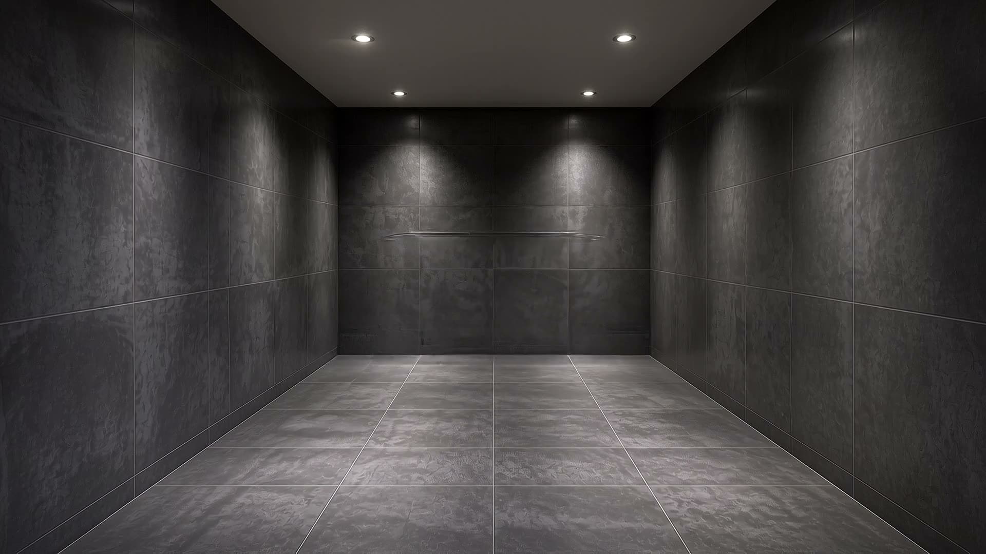 An empty dark-tiled bathroom shell awaiting its bespoke interior